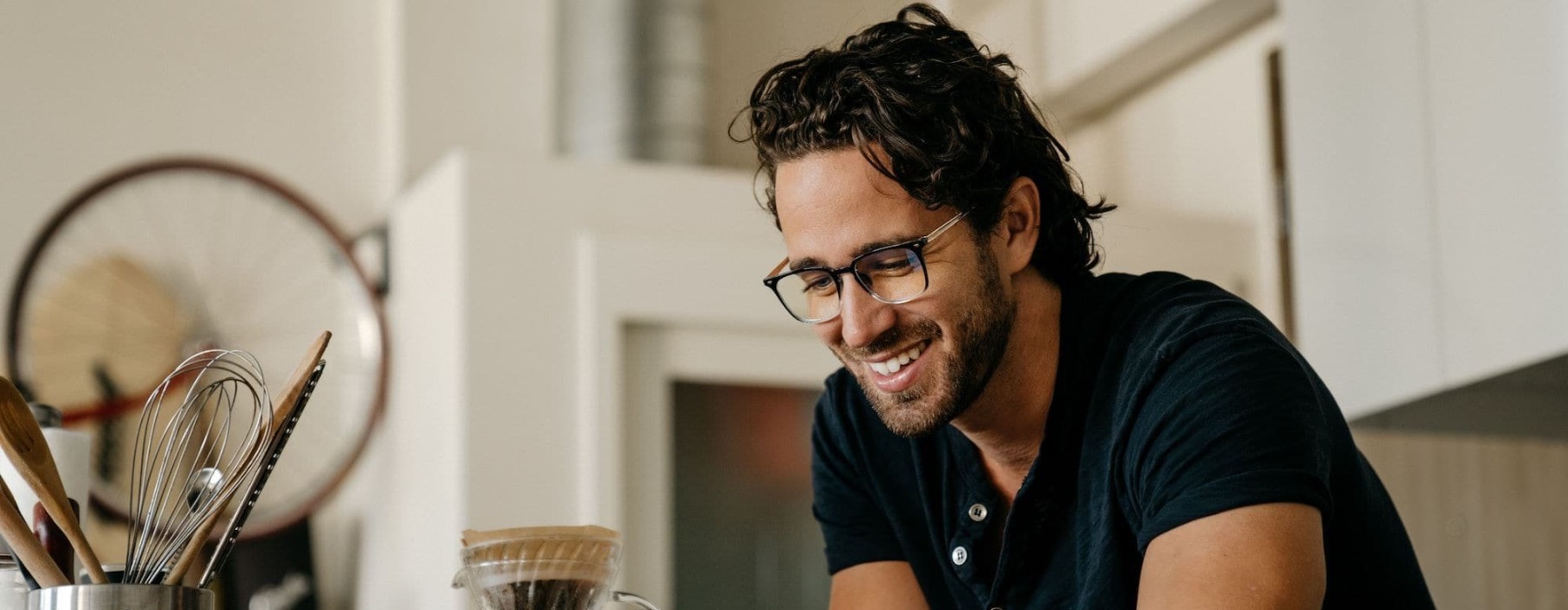 a man smiling as he looks at his device indoors